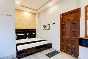 A bedroom with a bed, a wooden door, and a wall-mounted light fixture.