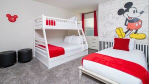 Ein Zimmer mit Etagenbetten, einem Schreibtisch und einer Wandmalerei mit Mickey Mouse.