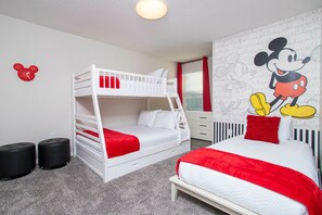 Una habitación con literas, un escritorio y un mural de Mickey Mouse.