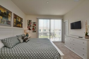 A bedroom with a bed, a nightstand, a dresser, a TV, and artwork on the walls. - 3BR townhouse near Disney | Private pool (Clermont)
