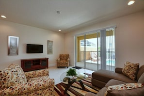 A living room with a sofa, armchair, and a glass coffee table. - 3BR townhouse near Disney | Private pool (Clermont)