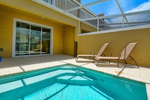 A pool area with a glass door leading to a covered patio. - 3BR townhouse near Disney | Private pool (Clermont)