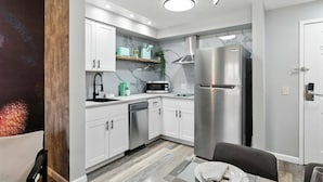 A modern kitchen with white cabinets, a stainless steel refrigerator, a microwave, and a dishwasher. - 1BR ADA apartment | 5 min to Epic Universe (Orlando)