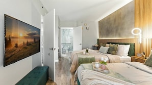 A modern bedroom with a large bed, a bench, and a painting on the wall. - 1BR ADA apartment | 5 min to Epic Universe (Orlando)
