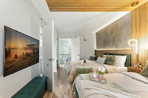 Un dormitorio moderno con una cama grande, un banco y un cuadro en la pared.