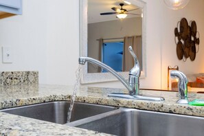 Una cocina con un lavamanos doble, un ventilador de techo y una lámpara fijada a la pared.