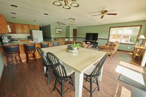 A spacious kitchen with a dining area, wooden cabinets, and a ceiling fan. - Riverfront Property Near Downtown Pella with Game Room, Fire Pit, and Yard Games (Pella)