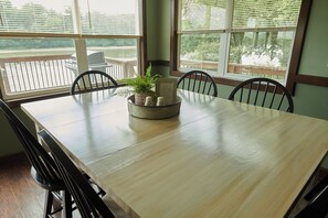 A dining table with chairs, a potted plant, salt and pepper shakers, and a framed note. - Riverfront Property Near Downtown Pella with Game Room, Fire Pit, and Yard Games (Pella)