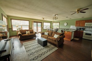 A spacious living room with two sofas, a coffee table, and a kitchen area with a stove and microwave.