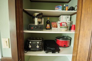 A kitchen with a coffee maker, a slow cooker, and a toaster on the shelves. - Riverfront Property Near Downtown Pella with Game Room, Fire Pit, and Yard Games (Pella)