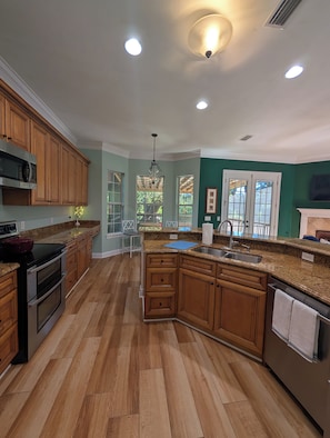 A kitchen with wooden cabinets, a granite countertop, a stainless steel sink, and a built-in oven. - Walkable Midtown Retreat-Spacious 4BR/3BA & Screened Porch- Near FSU & Downtown (Tallahassee)