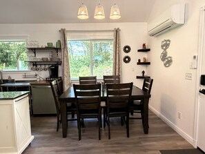 Un comedor con mesa y sillas, una cocina con ventanal y elementos decorativos en la pared.