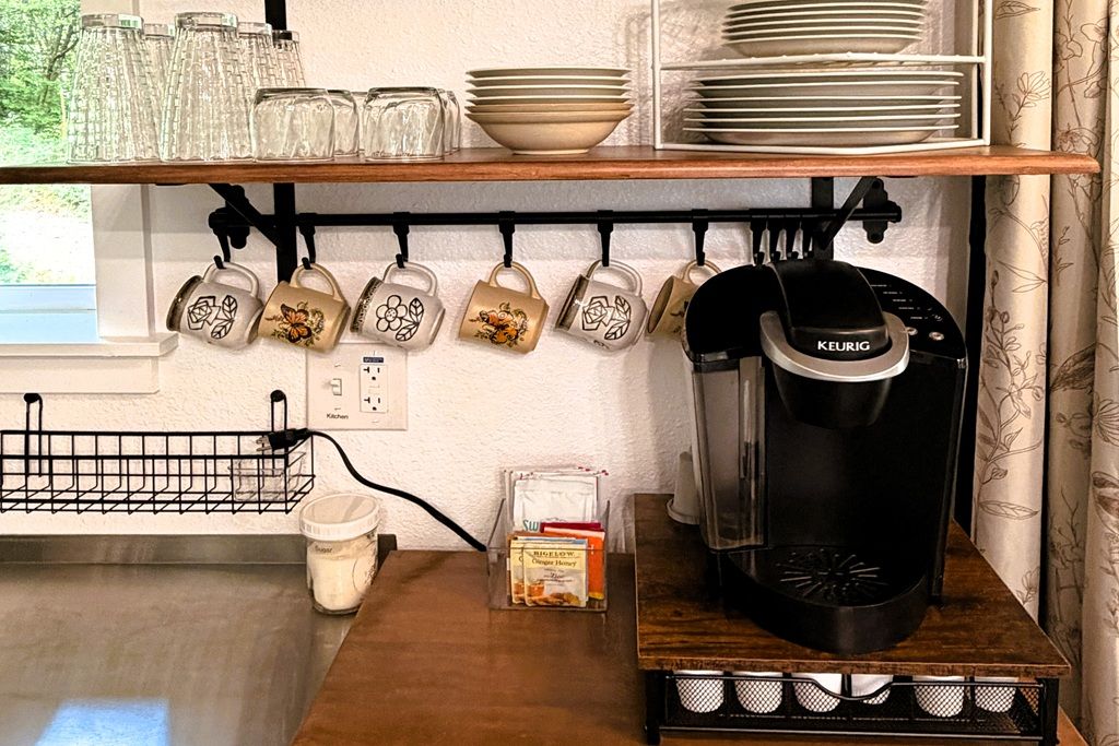 A kitchen with a coffee maker, mugs, and a milk jug.