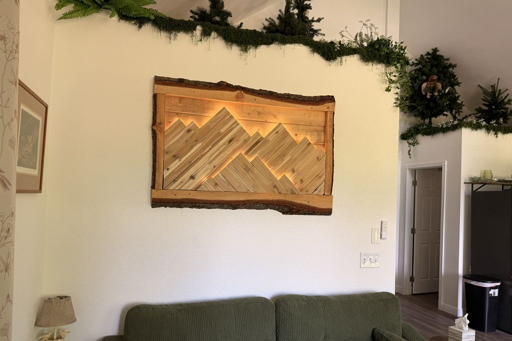 A living room with a green sofa, a wooden wall decoration, and a door in the background.