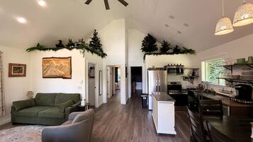 A spacious living area with a green sofa, a dining table, and a kitchen with modern appliances.