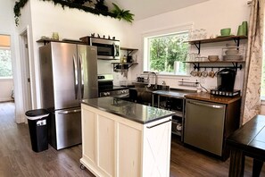 A modern kitchen with stainless steel appliances, a central island, and a window providing a view of greenery outside.
