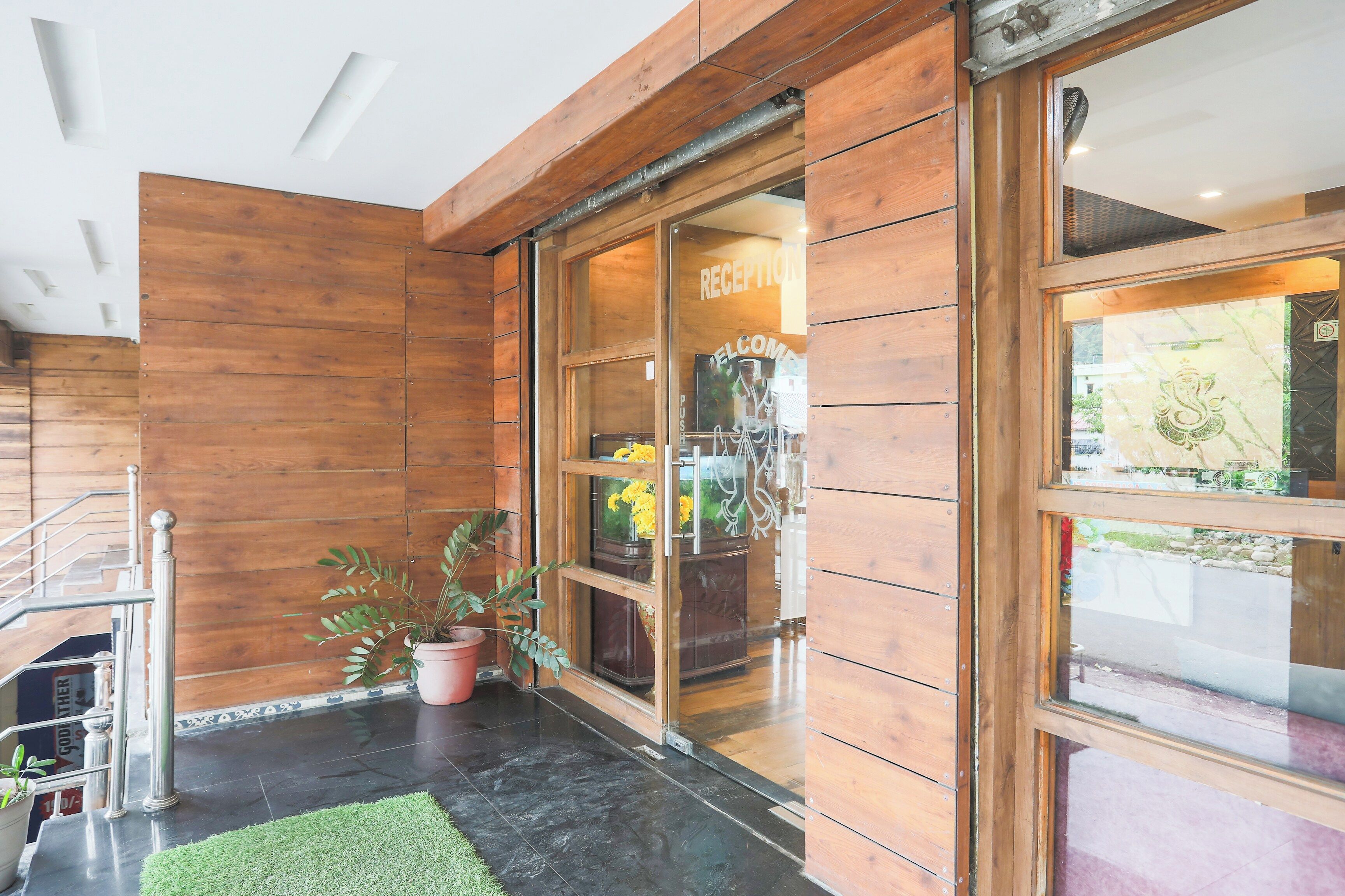 A reception area with a wooden interior, a glass door, and a potted plant.