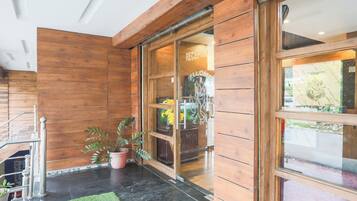 A reception area with a wooden interior, a glass door, and a potted plant.
