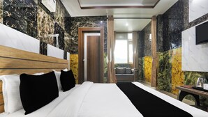 Quarto de hotel com uma cama grande, cabeceira de madeira, TV de tela plana e vista para o exterior pela janela.