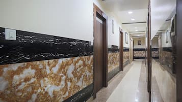 A hotel corridor with marble walls, doors, and a tiled floor.
