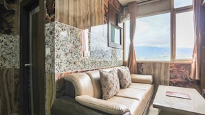 Quarto com sofá, mesa e vista pela janela.