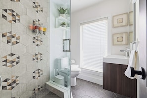 A modern bathroom with a shower, toilet, and sink area. - Stylish 2BR Retreat | Private Patio & Free Park (Toronto)