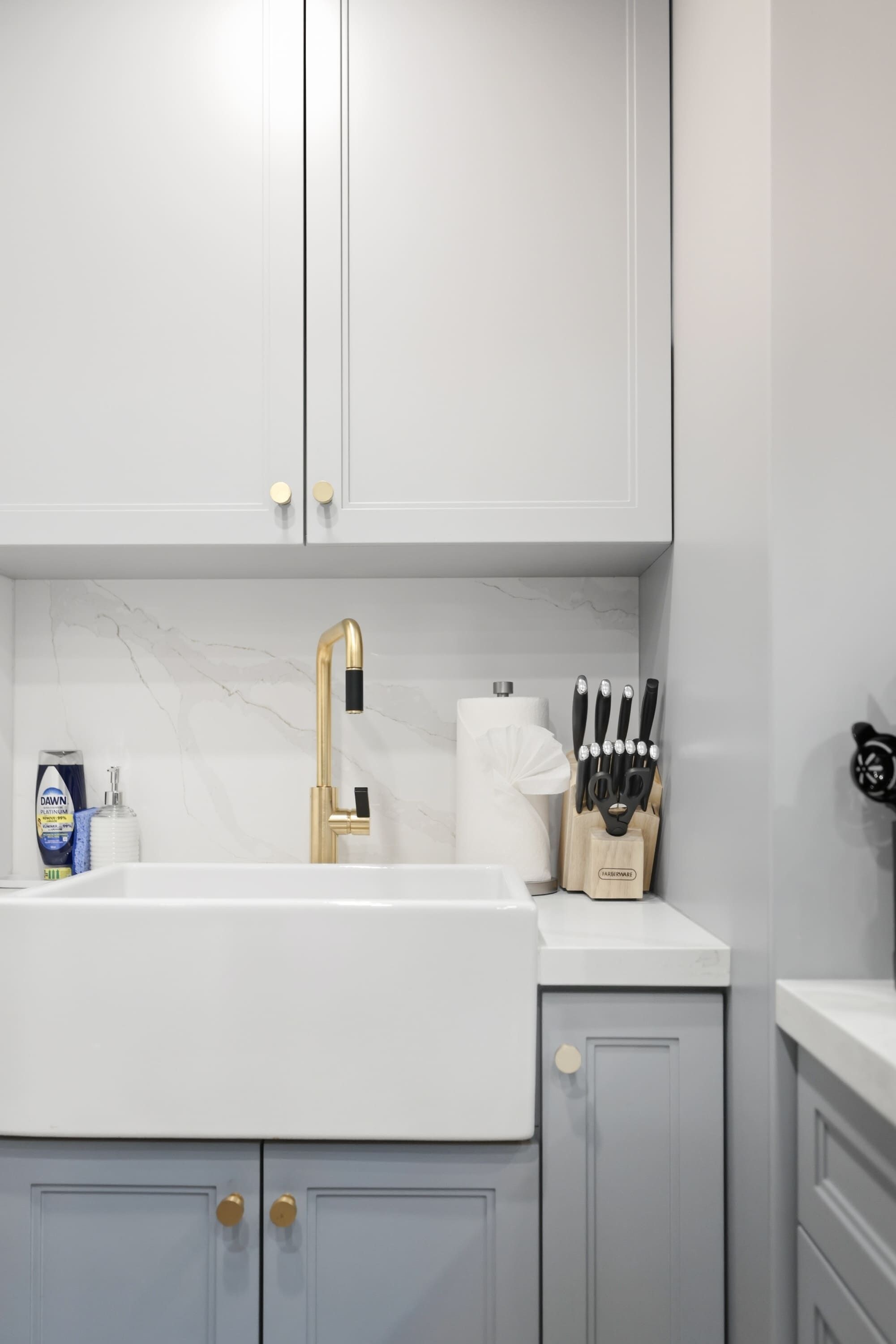 Una cocina con encimera blanca, grifo dorado y un bloque de cuchillos.