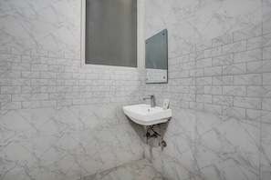 Un baño con un lavabo blanco, un espejo y una ventana.