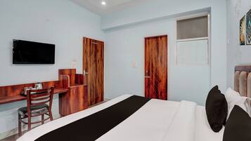 Una habitación de hotel con cama, escritorio, silla y televisor.