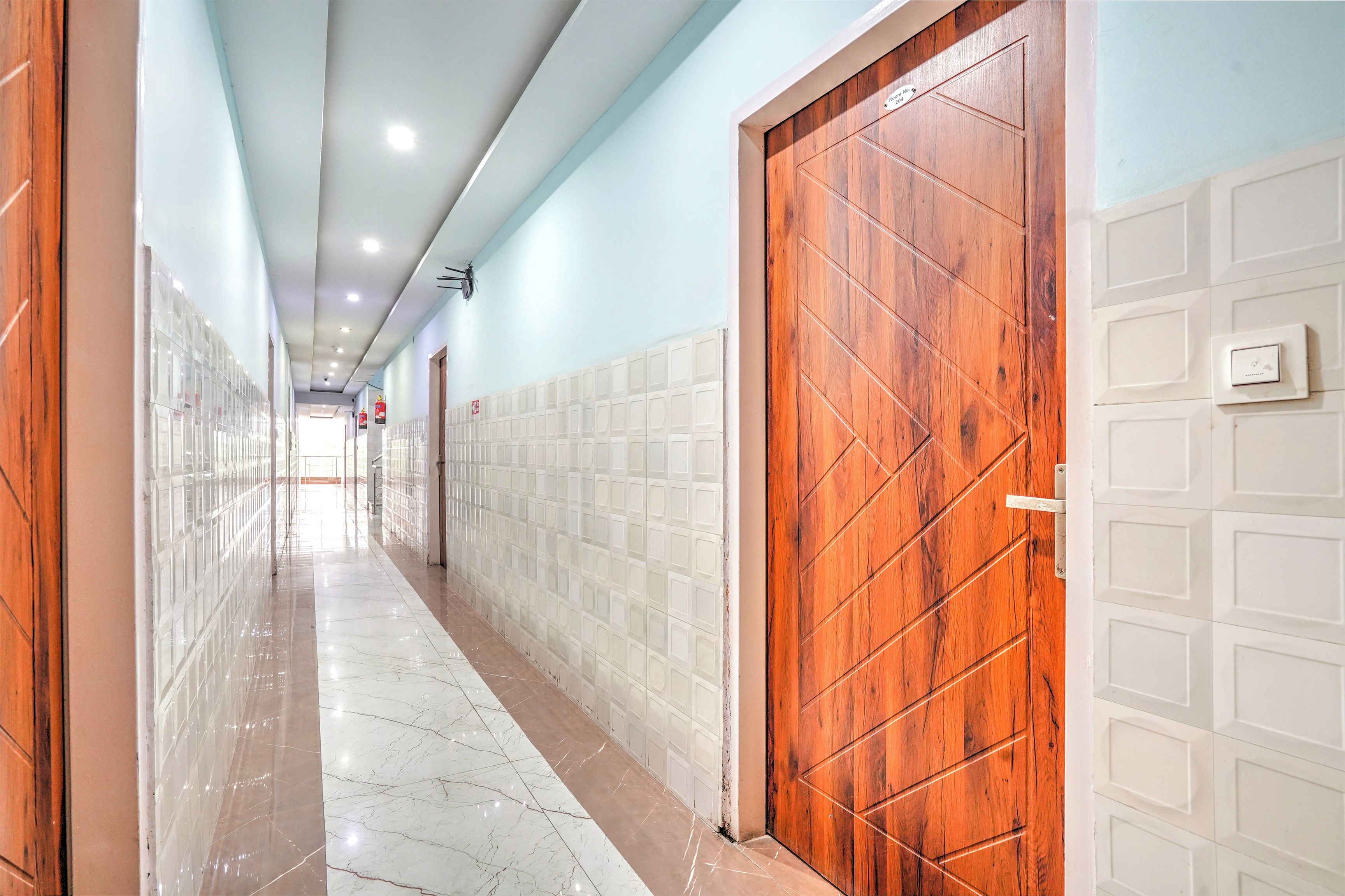 Um corredor com piso de azulejos, portas de madeira e parede azul clara.