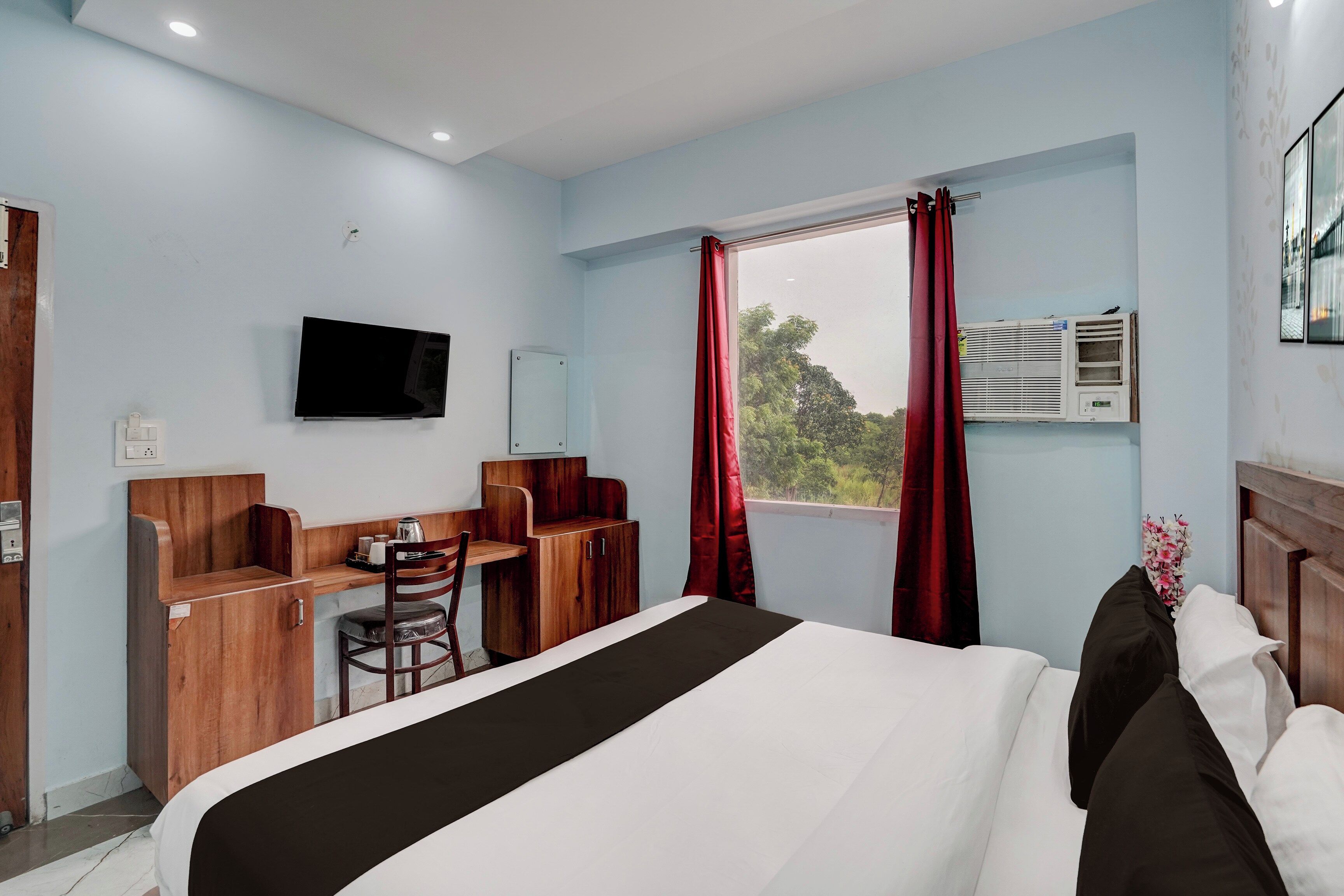 A hotel room with a bed, a desk, a chair, a television, and a window with curtains.