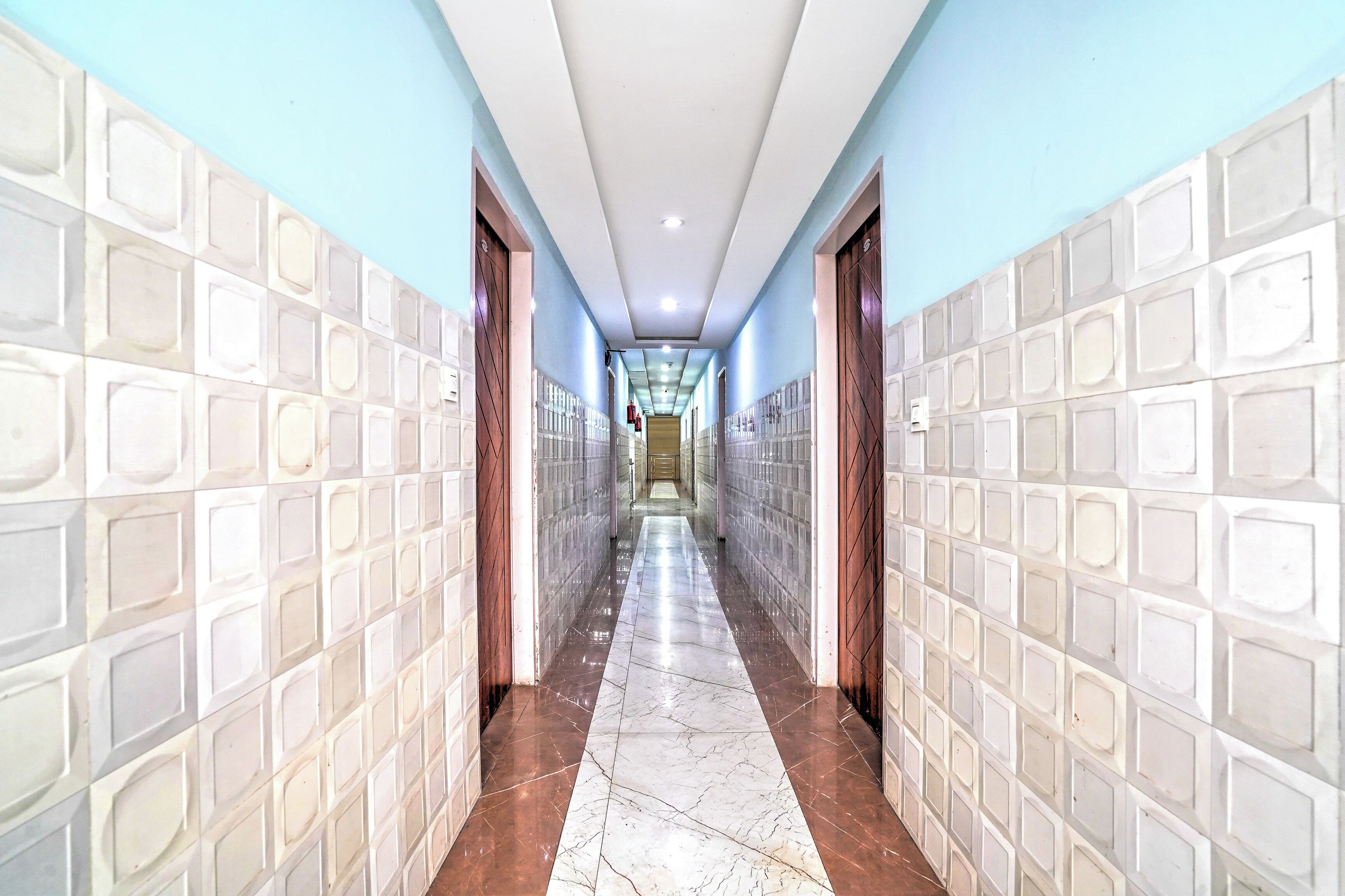 A corridor with tiled walls and a marble floor, leading to a door at the end.