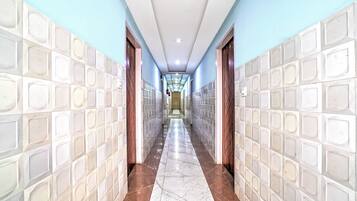 A corridor with tiled walls and a marble floor, leading to a door at the end.