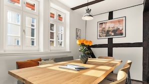 A dining area with a wooden table, chairs, a vase with flowers, and artwork on the wall. - Vrbo Property (Bad Hersfeld)