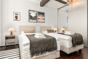 Quarto de hotel moderno com duas camas, um tapete listrado e obras de arte nas paredes.