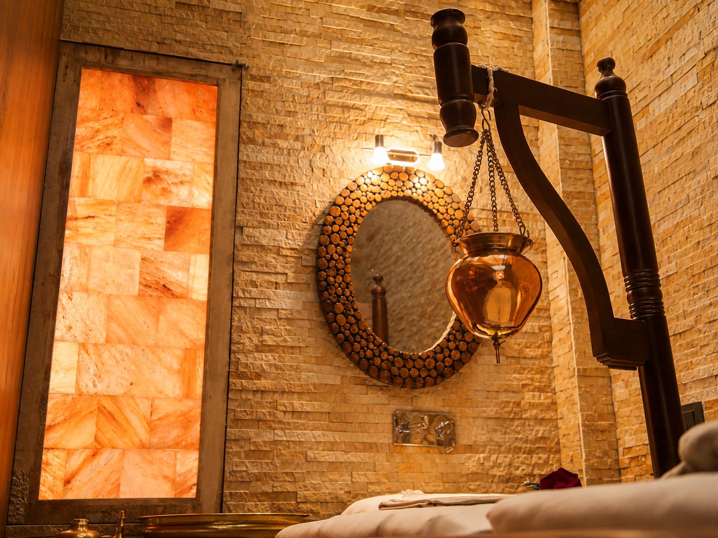 A bathroom with a stone wall, a round mirror with a wooden frame, and a hanging light fixture.