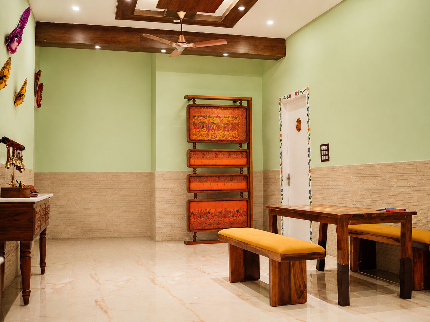 Quarto com um banco de madeira, uma mesa pequena, um ventilador de teto e uma porta com moldura decorativa.