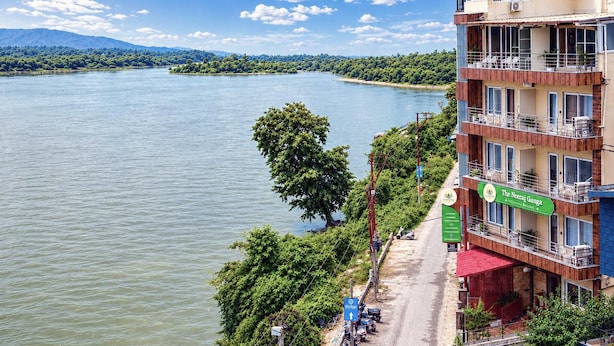 Ein Hotel mit Blick auf einen Fluss, einem Parkplatz und einem Schild für The Neeraj Ganga.
