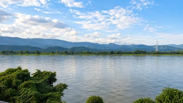 A river with mountains in the background and a power line tower on the right.