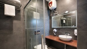 Ein modernes Badezimmer mit einer gläsernen Duschkabine, einem weißen Waschbecken und einem großen Spiegel.