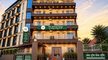 A multi-story wellness retreat building with balconies, a signboard, and potted plants.