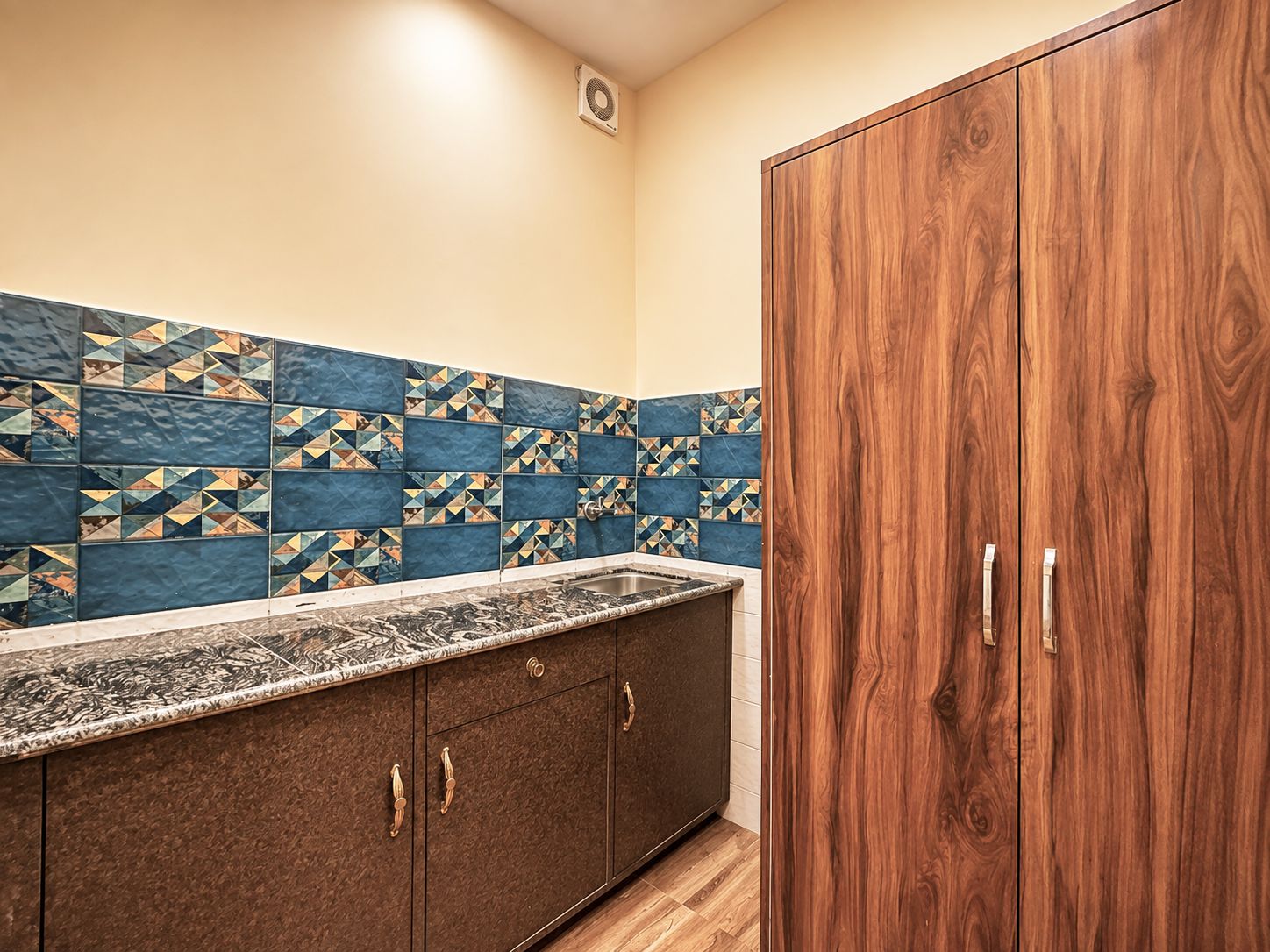 Una cocina con salpicadero de azulejos, armarios de madera y encimera de mármol.