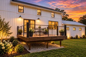 Une maison à deux étages dotée d’un patio couvert, d’un espace salon extérieur et d’un jardin bien entretenu.