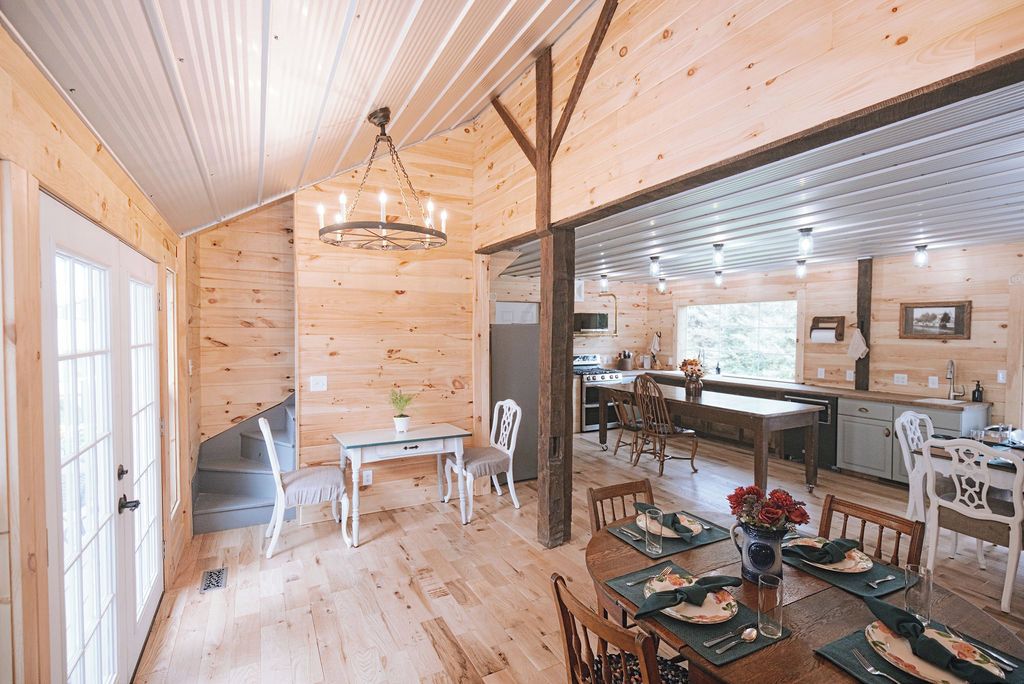 A wooden interior with a dining area, kitchen, and a staircase.