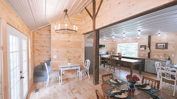 A wooden interior with a dining area, kitchen, and a staircase.