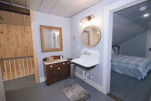 Un baño con tocador de madera, un lavabo y dos espejos.