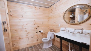 A wooden-paneled bathroom with a toilet, sink, and mirror. - 4-bedroom farmhouse near Pataskala with proximity to Columbus and Hocking Hills (Pataskala)