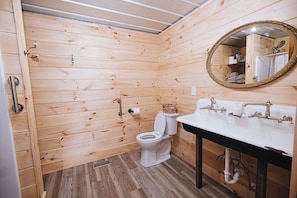 Een betegelde badkamer met toilet, wastafel en spiegel.