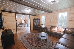 A wooden interior with a sofa, coffee table, and a patterned rug.