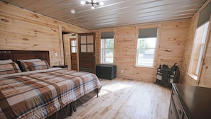 A wooden cabin bedroom with a bed, dresser, and a window. - 4-bedroom farmhouse near Pataskala with proximity to Columbus and Hocking Hills (Pataskala)